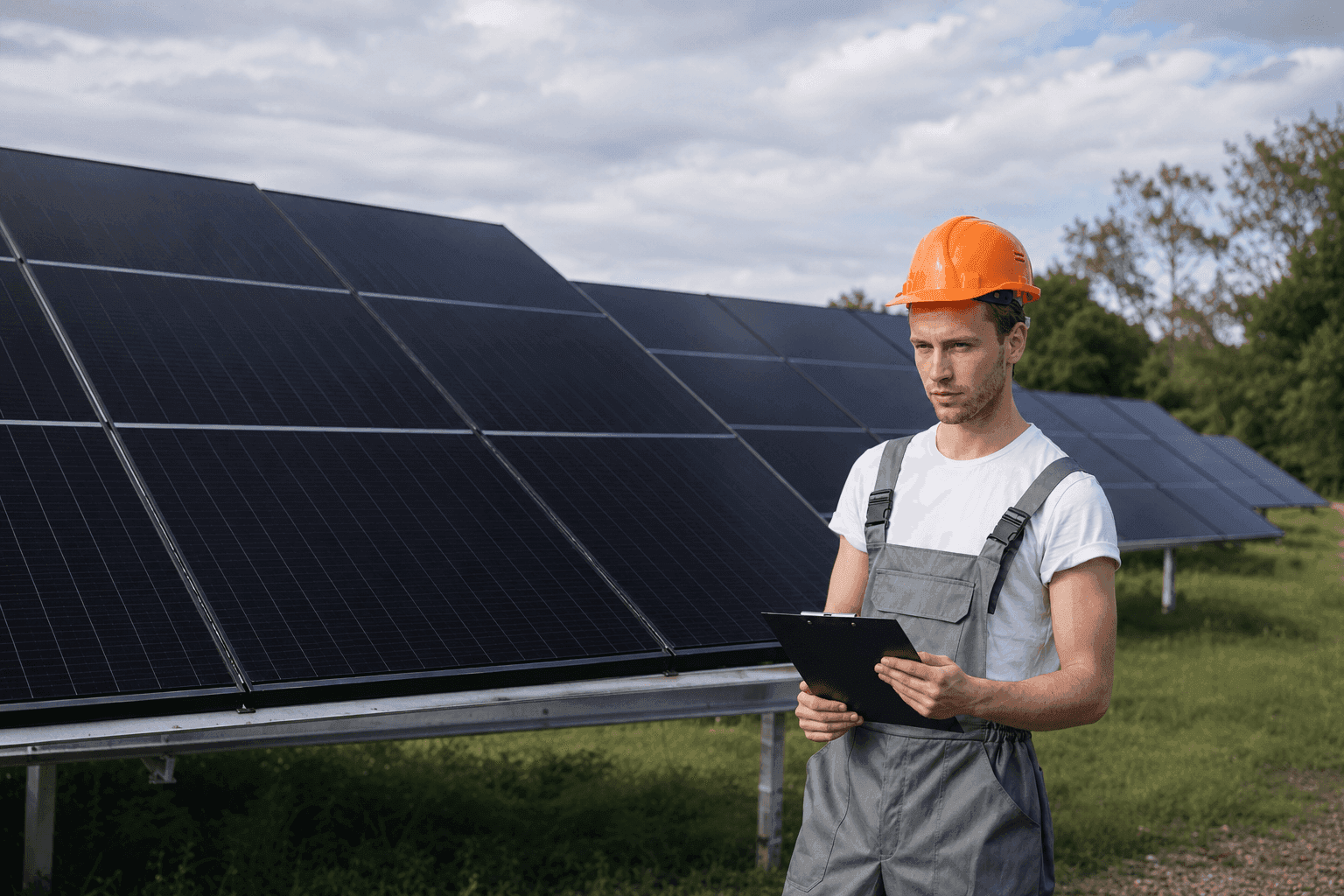 Engineer in a hard hat with a clipboard near solar panels